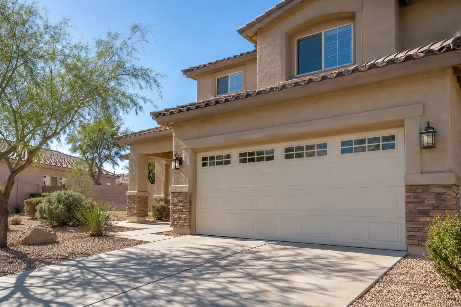 Two story tan stucco home with a cream raised panel garage door with top windows